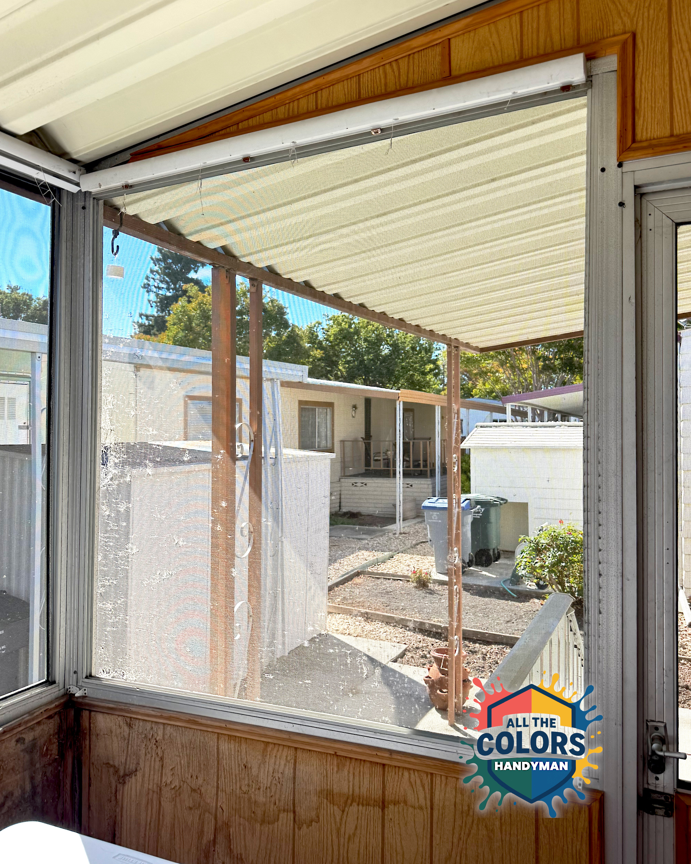 An inside view of a screened porch. The very large window screen has been trashed with big holes in some places.