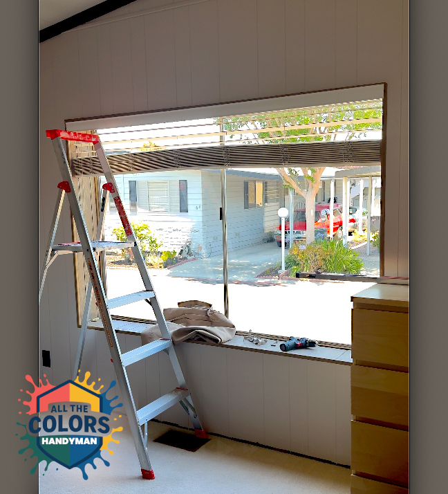 Still from vertical video showing a very wide window. A step ladder stands on the carpet in front of the window. A blind with wide slats hangs from the top of the window. The ends of it are sagging. It looks very heavy. Some fabric and a cordless drill rest on the wide window sill.